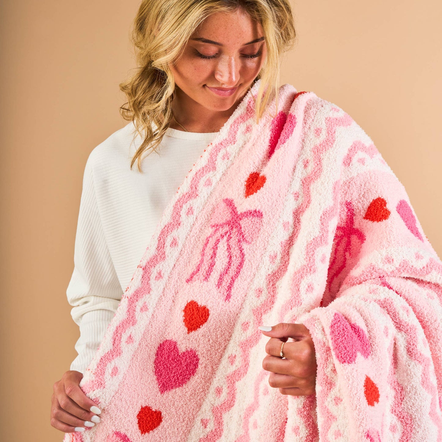 Cozy pink blanket with heart patterns, made from soft material, perfect for snuggling.