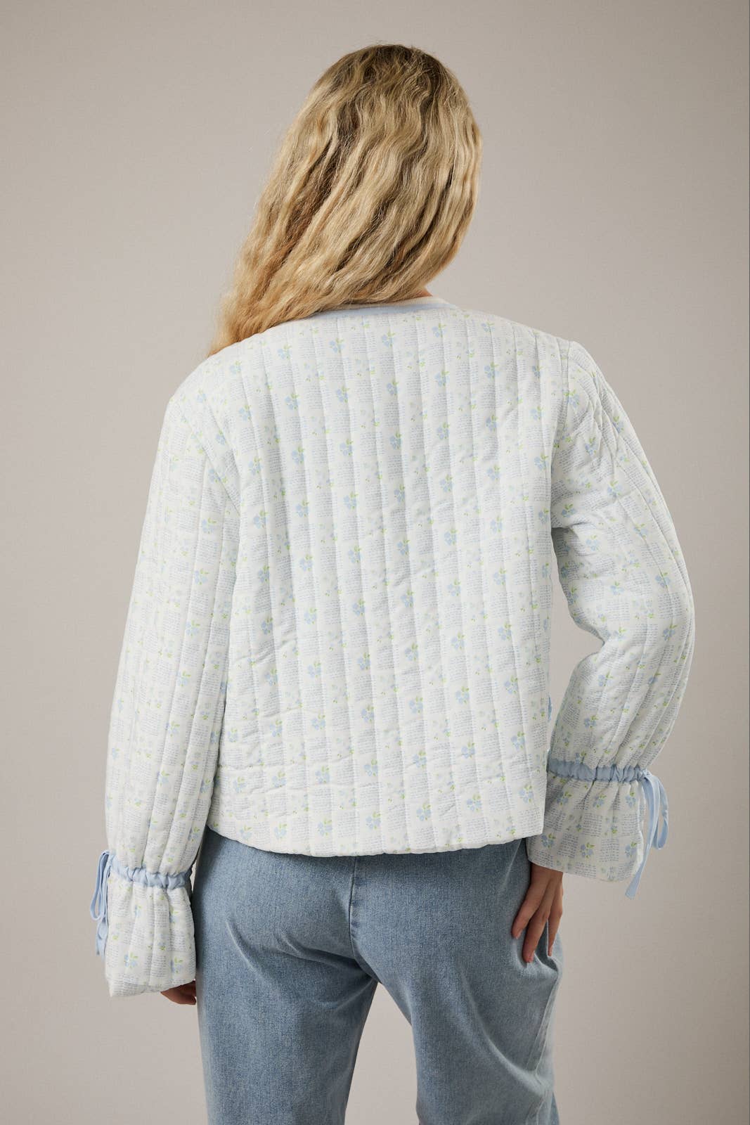 Women's quilted jacket in light blue with floral pattern and gathered sleeves, perfect for casual style.