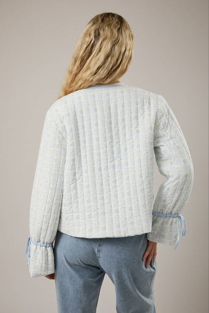 Women's quilted jacket in light blue with floral pattern and gathered sleeves, perfect for casual style.