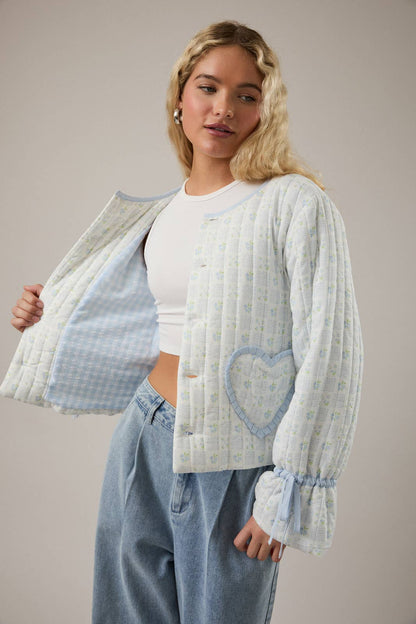 Light blue quilted cardigan with heart pocket, floral pattern, and ruffled sleeves.