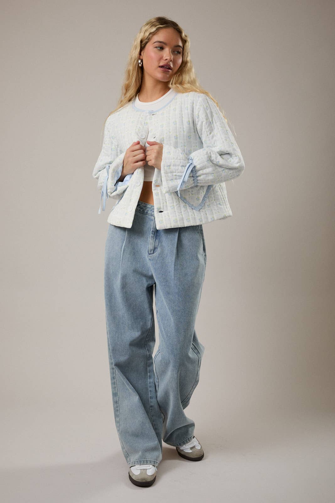 Women's quilted jacket in light blue, featuring wide sleeves and button closure, paired with light denim jeans.