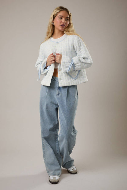 Women's quilted jacket in light blue, featuring wide sleeves and button closure, paired with light denim jeans.