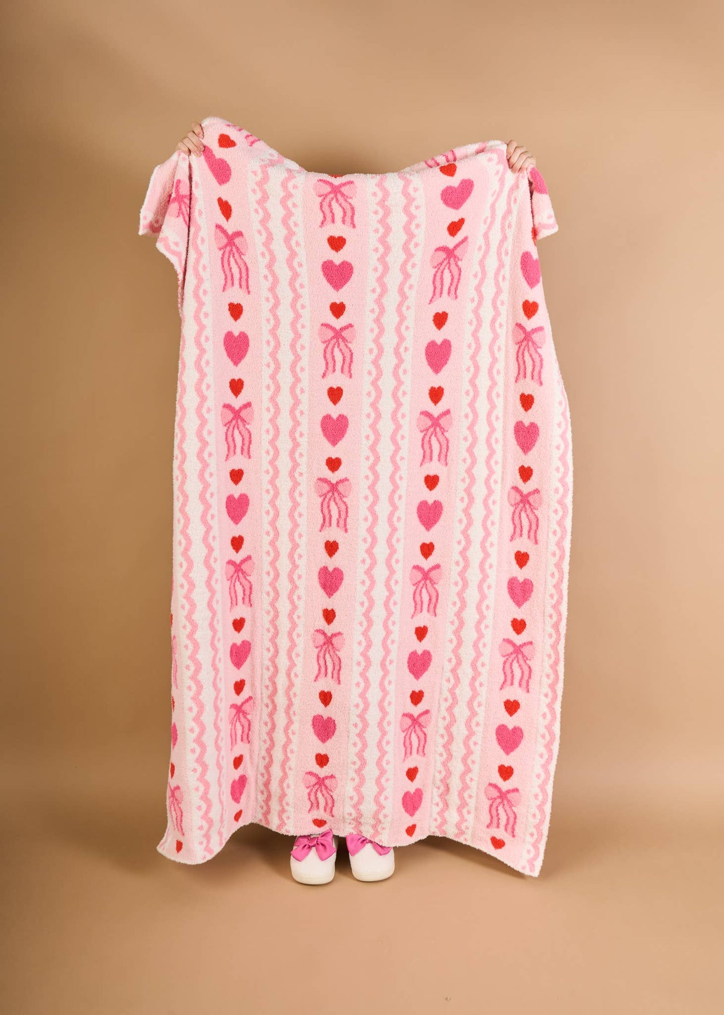 Cozy pink blanket with heart and bow patterns, perfect for adding charm to any room.