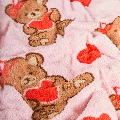 Cozy pink teddy bear blanket with heart patterns, soft plush material, perfect for cuddling.