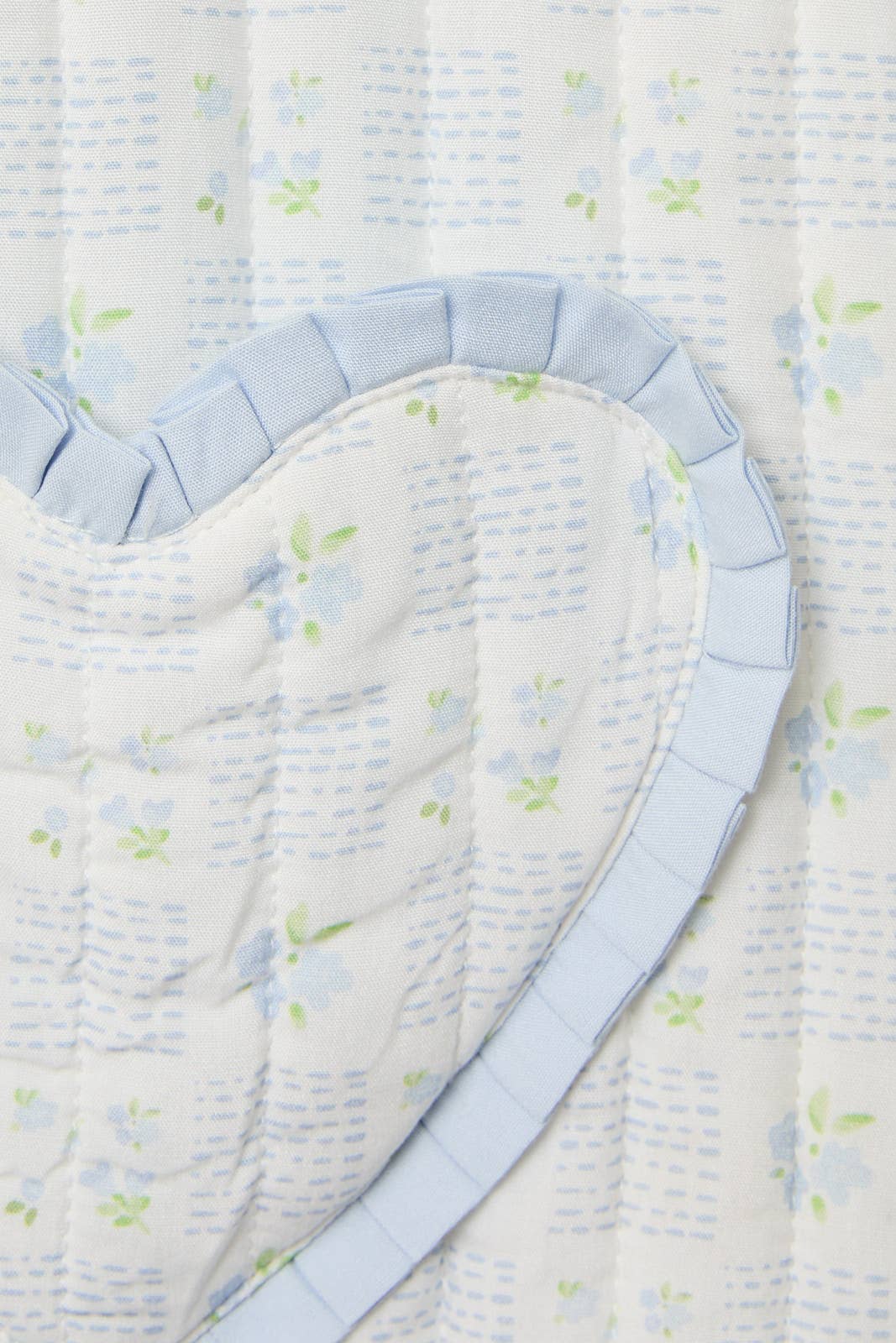 Light blue floral quilted bedding with heart-shaped pattern and ruffled trim for a cozy bedroom decor.
