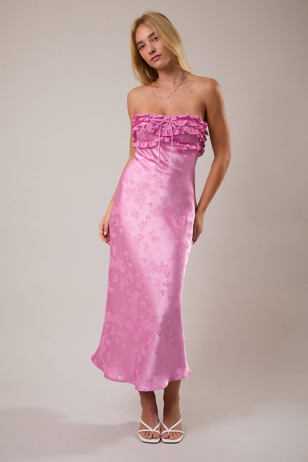 Stylish pink satin maxi dress with ruffled strap design and floral details, perfect for summer occasions.