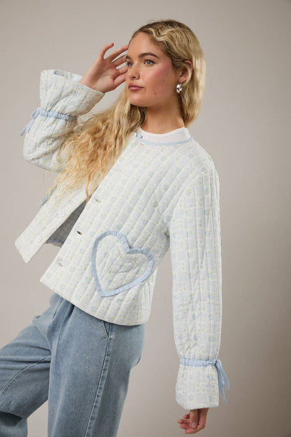 Quilted women's jacket in light blue with heart detail, stylish design and comfortable fit.