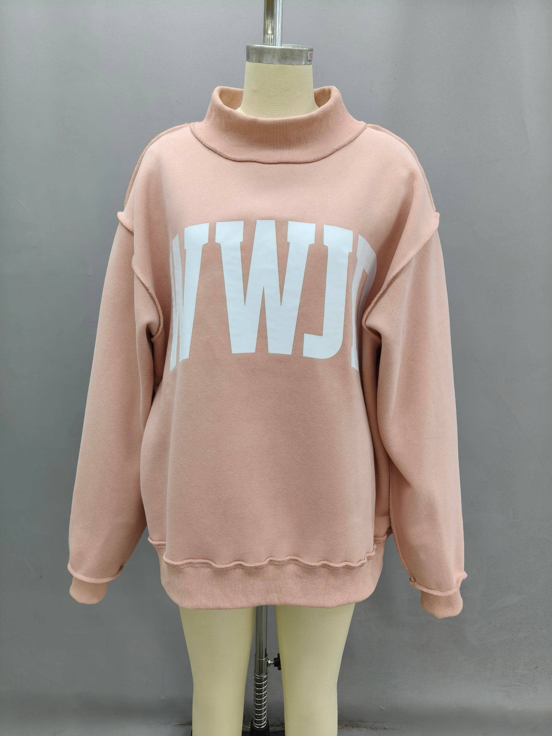 Oversized pink sweatshirt with a white logo, featuring a mock neck and cozy material.
