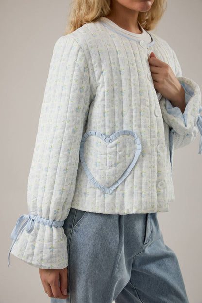 Cute quilted jacket in light blue with floral print, features heart patch and ruffled sleeves.