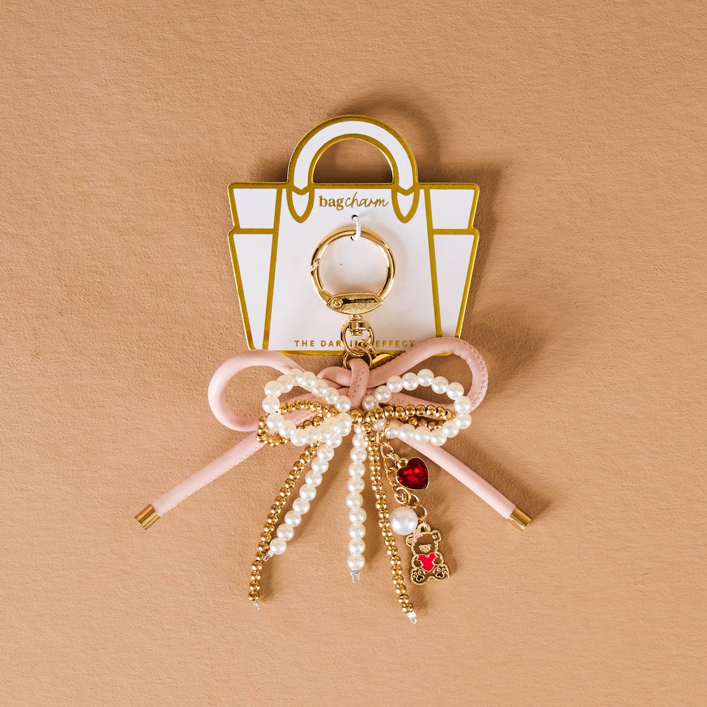 Chic pink bow bag charm with pearls and teddy bear pendant, ideal for adding style to any handbag.