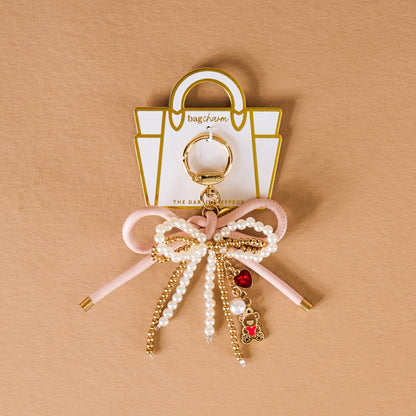 Chic pink bow bag charm with pearls and teddy bear pendant, ideal for adding style to any handbag.