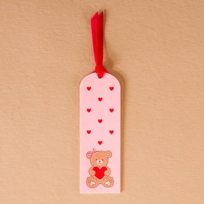 Cute pink bookmark featuring a teddy bear and red hearts, perfect for gifts and reading lovers.