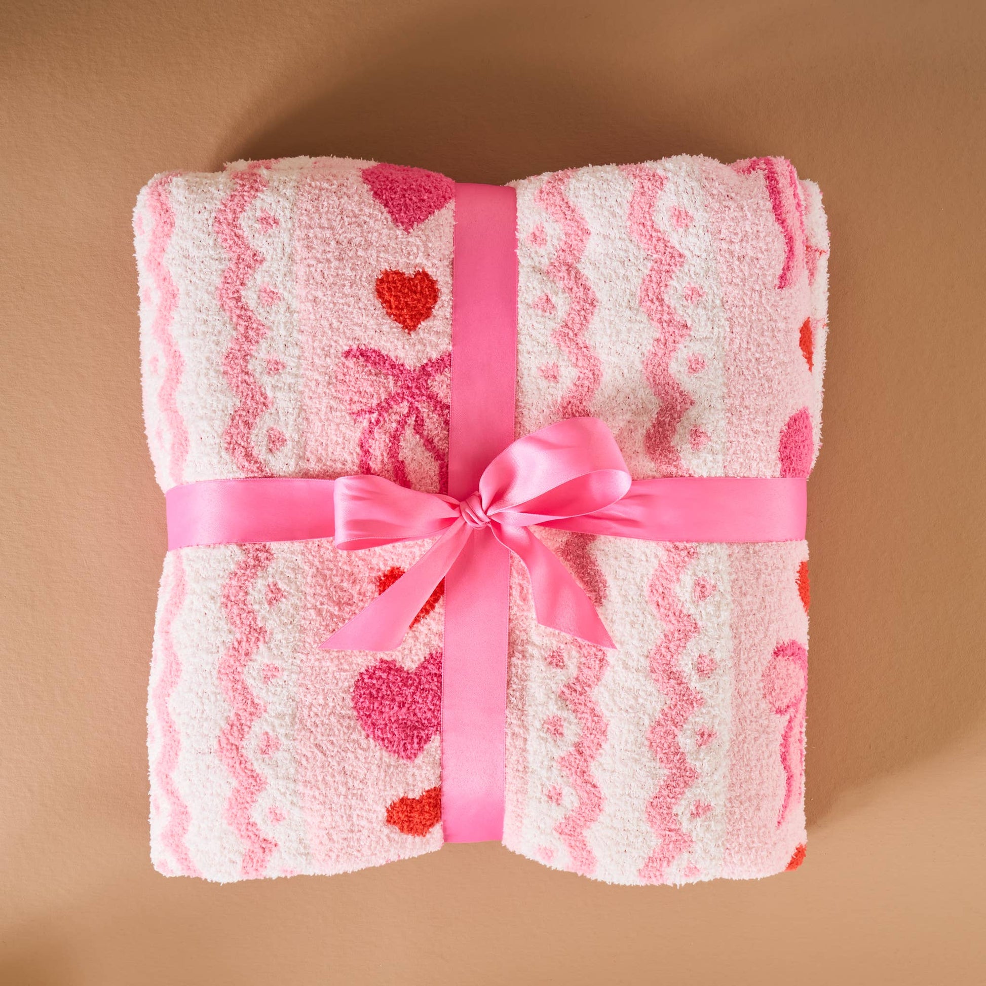 Soft pink bath towel with heart patterns, tied with a pink ribbon, perfect for gift-giving.