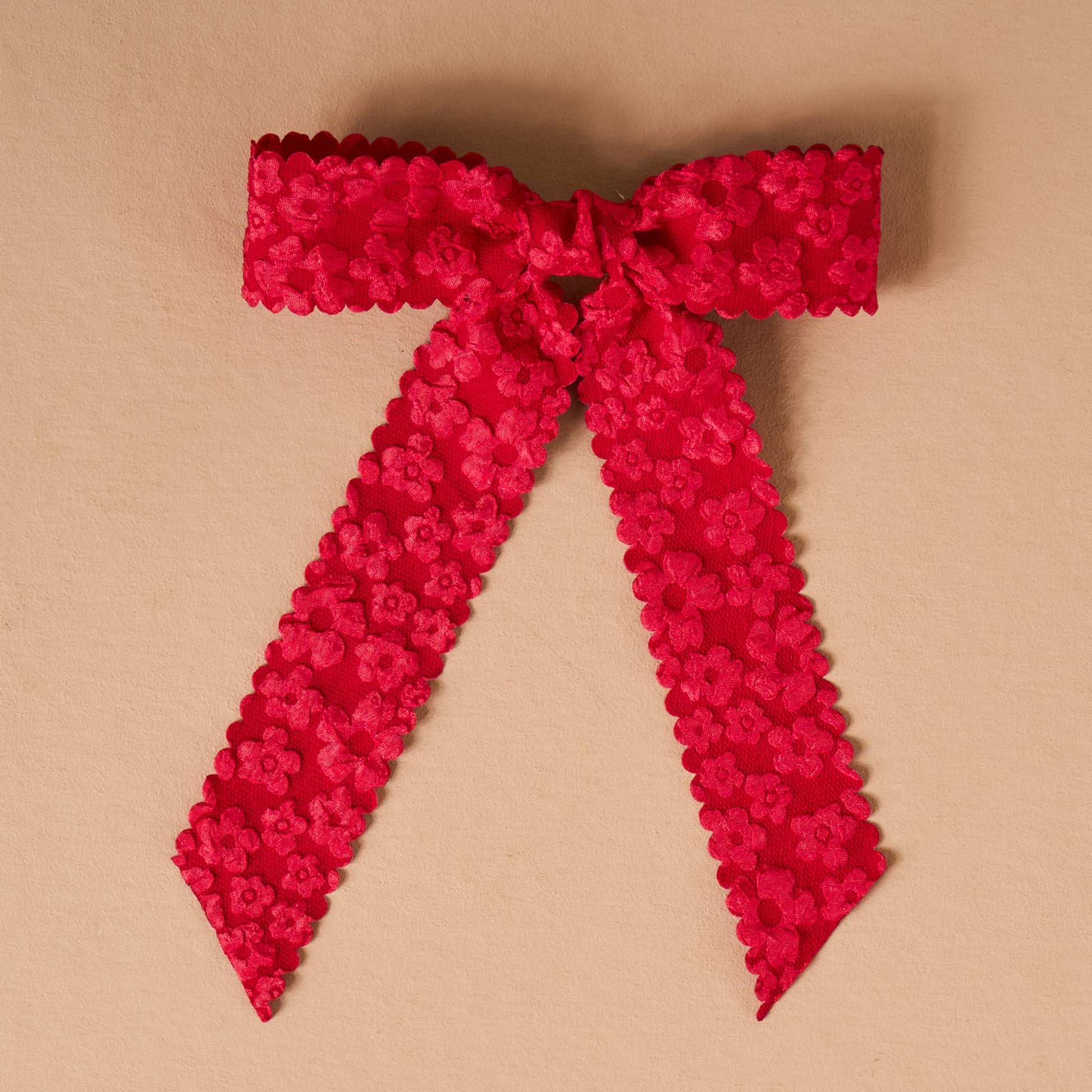 Red floral lace ribbon with scalloped edges, perfect for gifts and crafts.