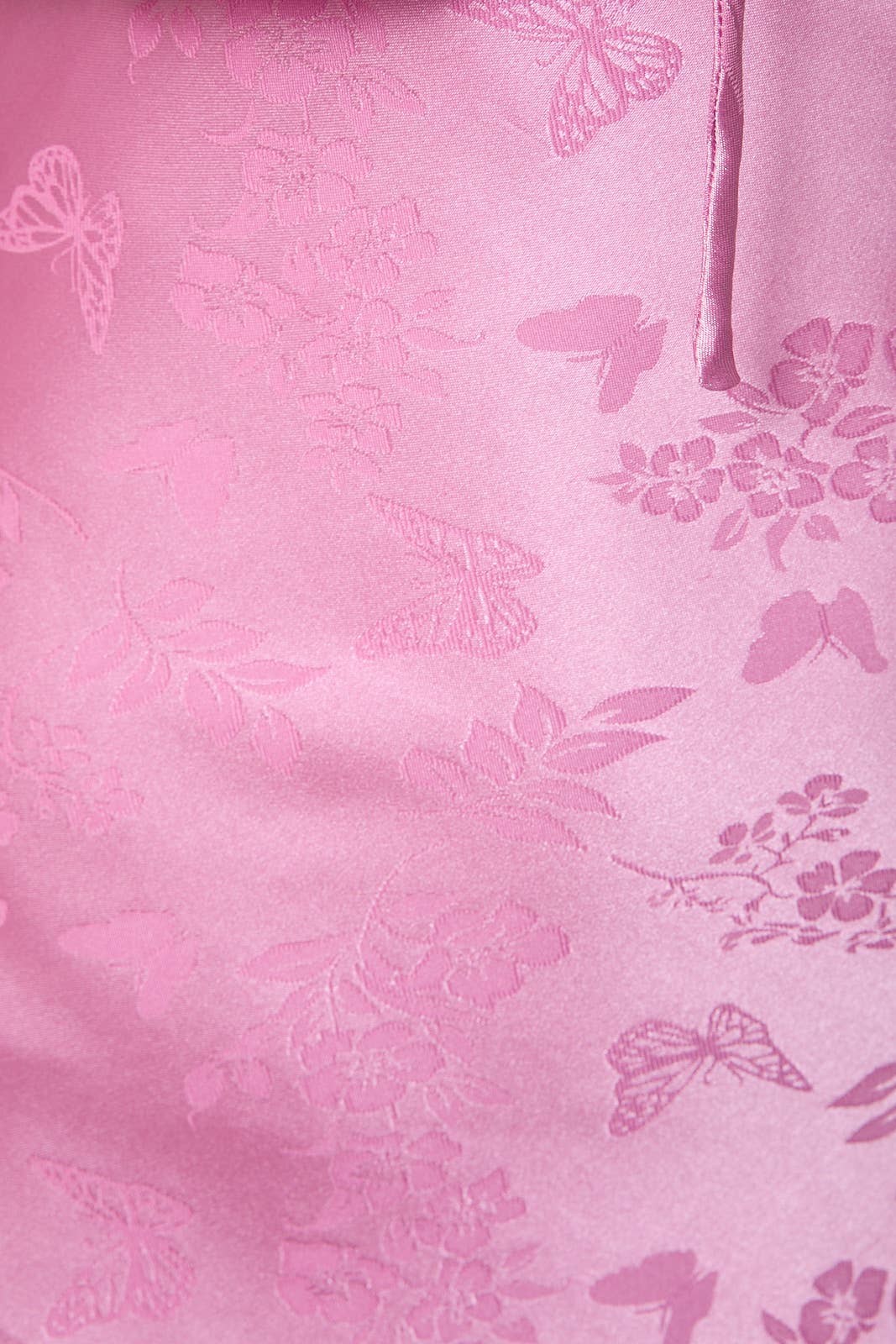 Soft pink satin fabric featuring floral and butterfly embossed patterns, perfect for elegant apparel.