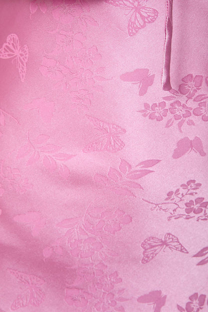 Soft pink satin fabric featuring floral and butterfly embossed patterns, perfect for elegant apparel.