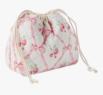 Quilted drawstring bag in white with pink roses and bows, perfect for stylish storage.