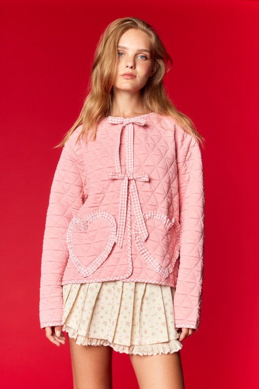 Quilted pink hoodie with heart pockets, bow detail, and cozy fabric, perfect for stylish layering.