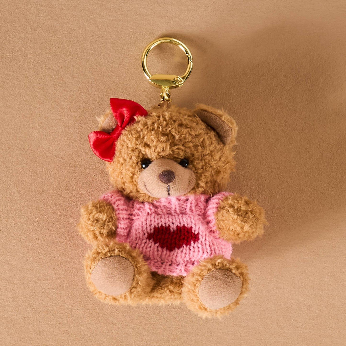 Cute plush teddy bear keychain with pink sweater and red bow, perfect for gifts and accessories.